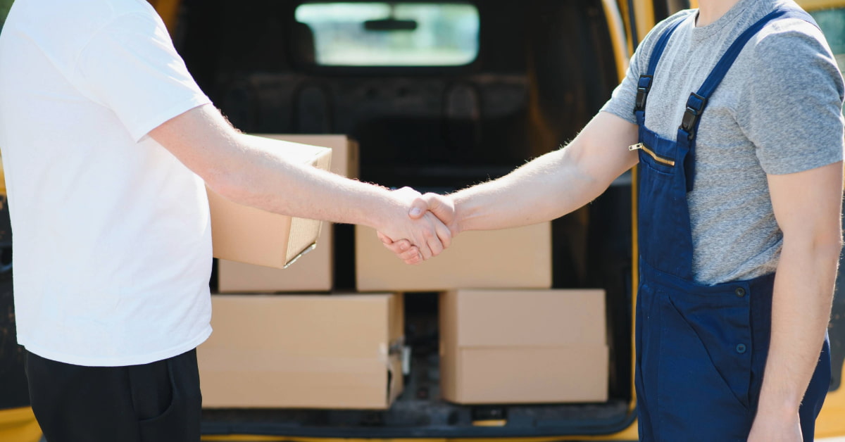 Dois profissionais apertando as mãos em frente a van de entregas simbolizando drop off