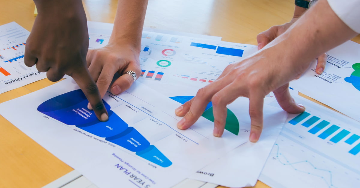 Pessoas analisando gráficos e apontando para um diagrama em formato de funil, representando como fazer um funil de vendas na prática